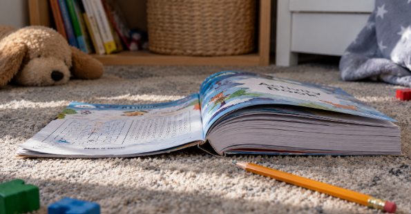 An open activity book lying face down on the floor with most of its pages unused 